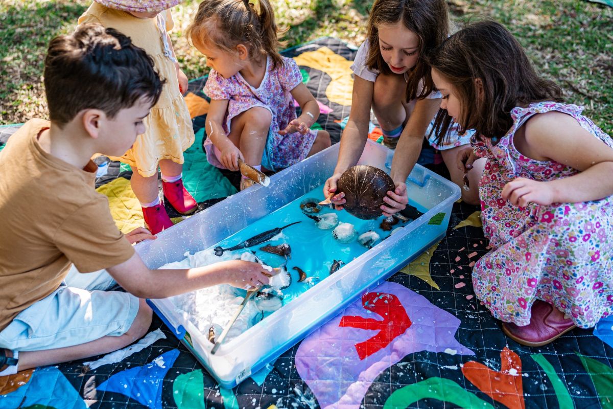 children engaged in a craft activity on a colourful blanket