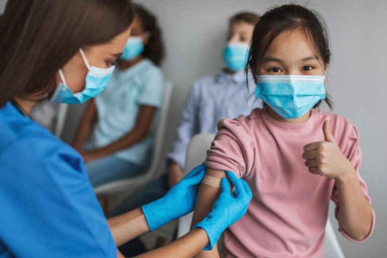 Asian girl giving thumbs up sign following a vaccine.
