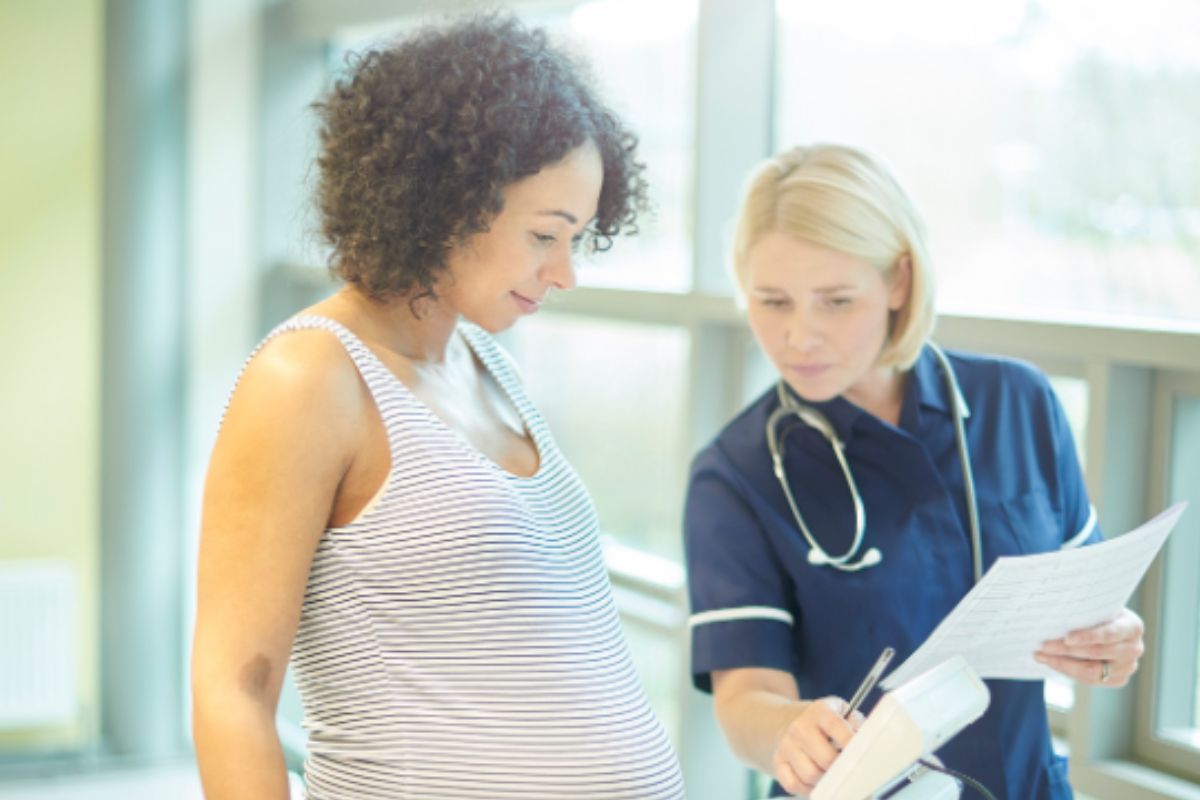 A pregnant woman and midwife conducting a weigh in.