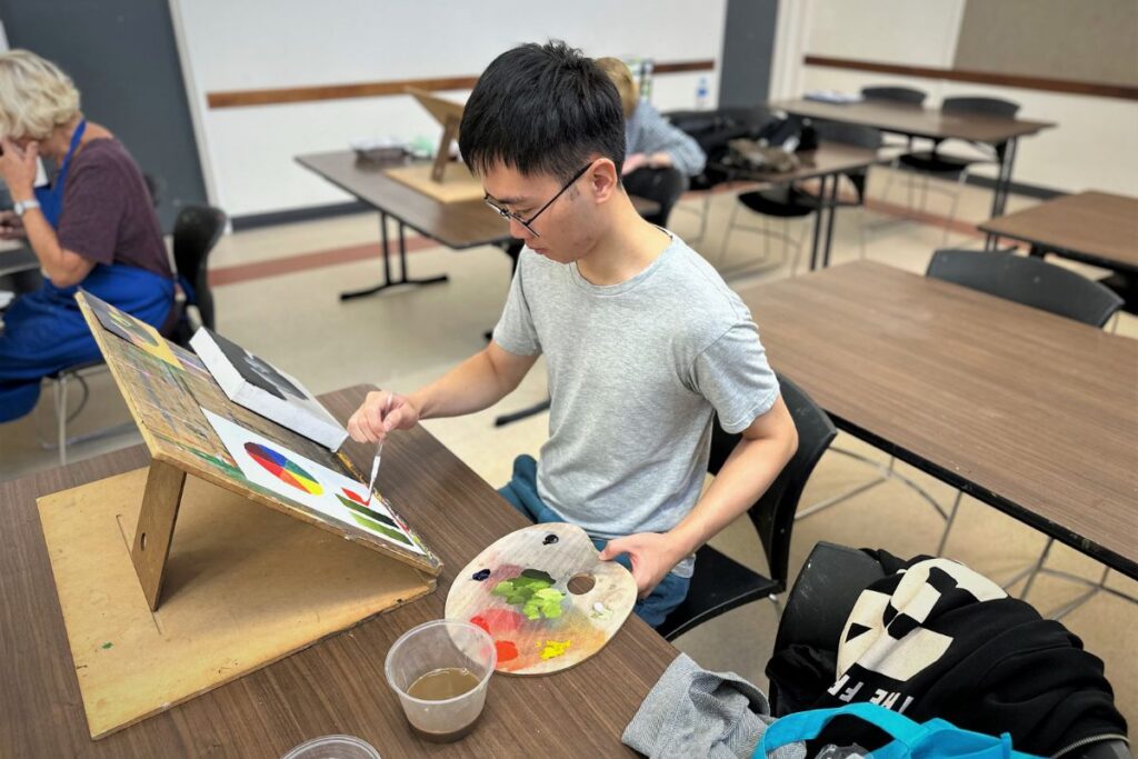 a student paints on a canvas during an art class.