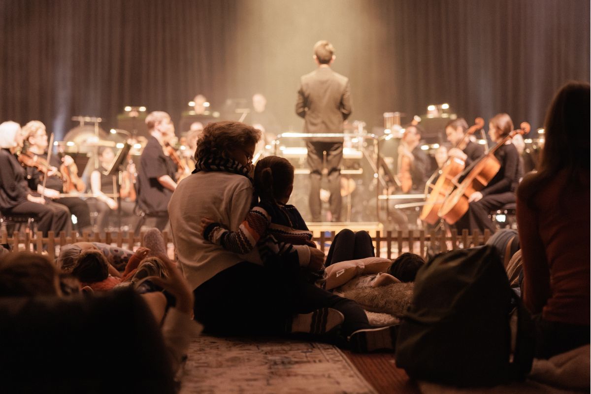 An orchestra plays to a crowd of families.