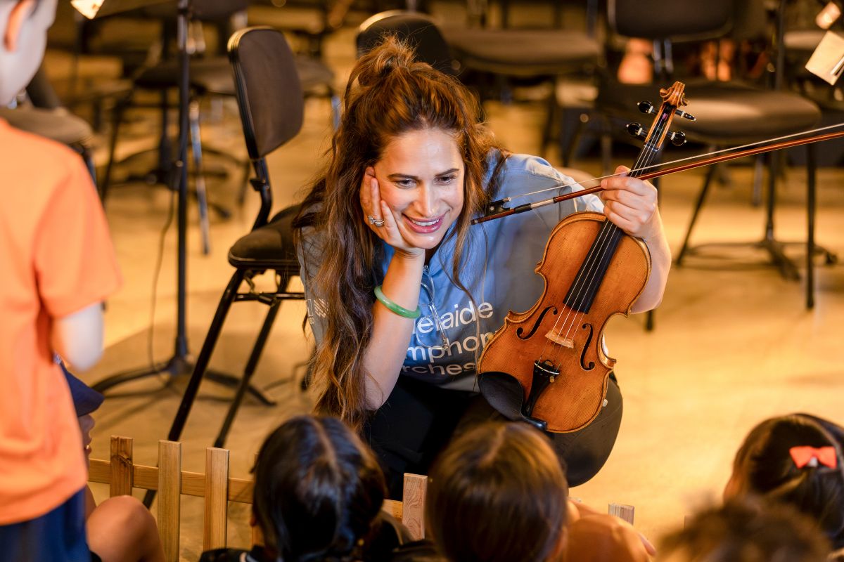 ASO musician Heidi Wolff holds her instrument whilst talking to a group of children.