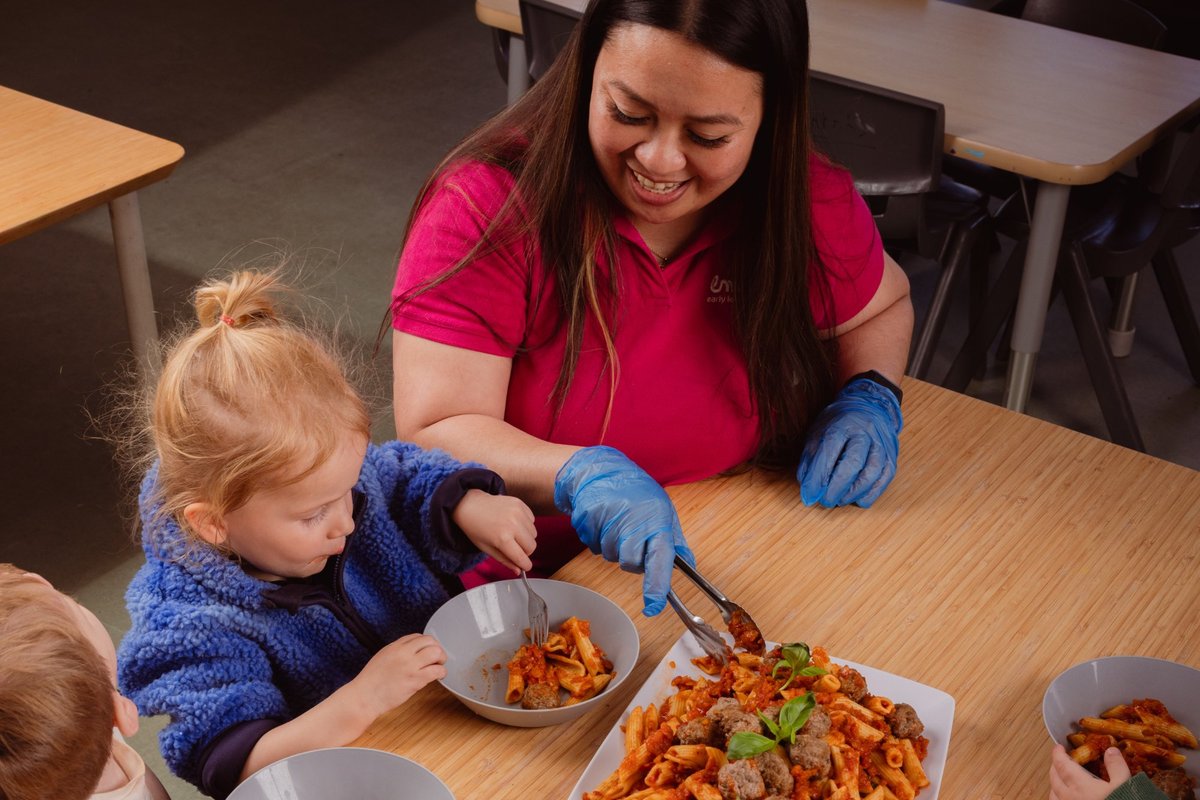 An Emali childcare worker serving food to a toddler.