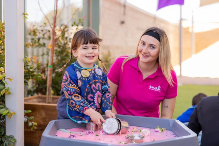 A child and adult play with sand in a childcare setting.