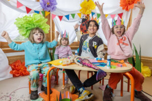 Carclew family art day - a group of varied age children sit in a vibrant art room.