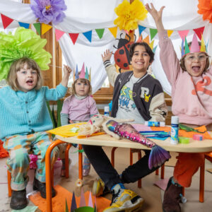 Carclew family art day - a group of varied age children sit in a vibrant art room.