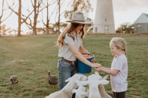 Two children feeding farm animals in a field.