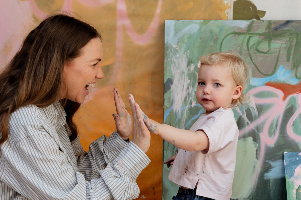 Artist Madeleine Collopy playing with her child in her art studio.