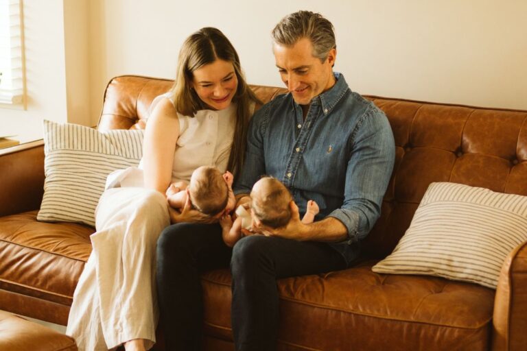 Parents sitting on a couch holding their twin babies