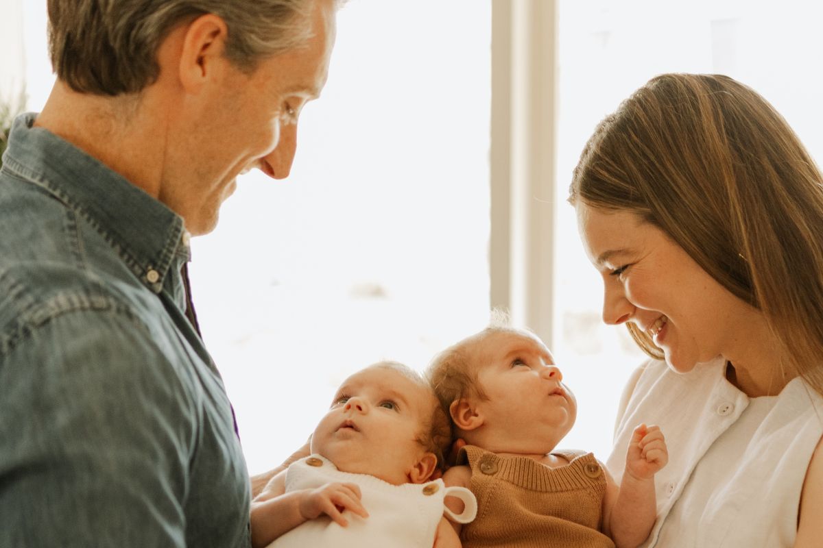 Parents standing and holding their twin babies together