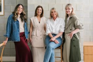 Four South Australian mums, founders of mumamoo, standing together against a neutral wall, smiling