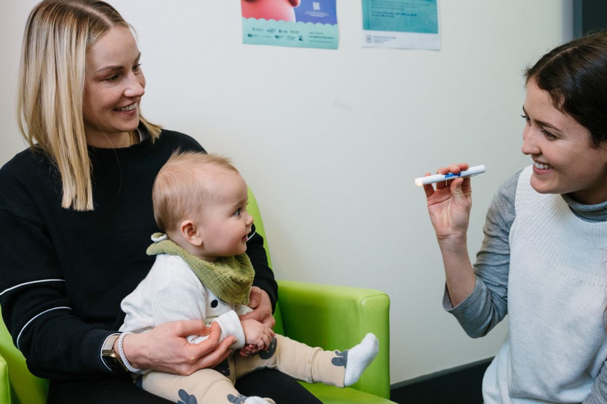 A mum and baby in a CAFHS appointment having their eyes examined by a nurse.