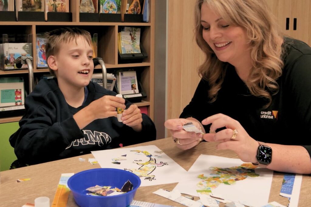 A Hospital School SA student and a Credit Union SA staff member work together on a collage artwork at a classroom table