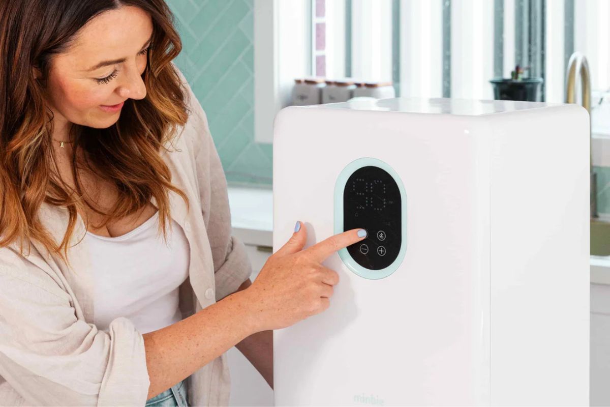 A woman demonstrating the Minbie baby bottle UV steriliser & dryer.