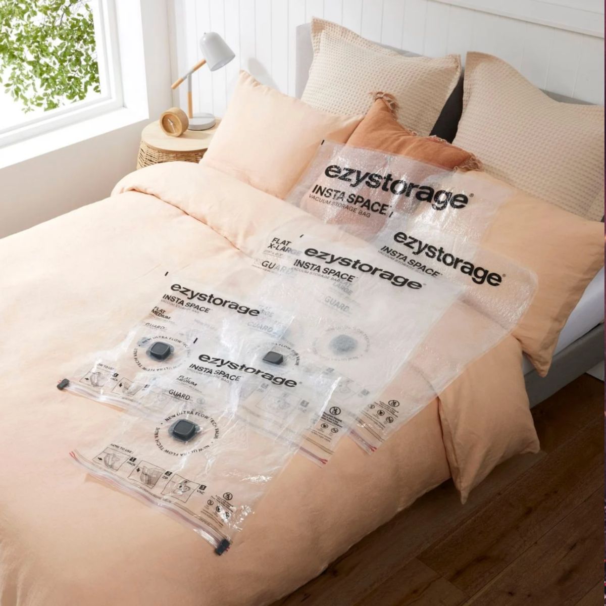 A freshly made bed with empty storage bags laid out.