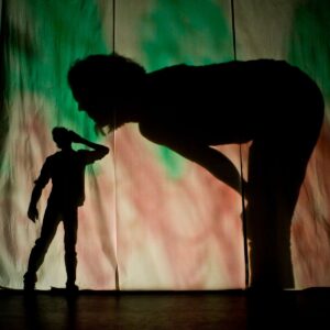 Me & My Shadow childrens production a man extending an ear to a giant woman bending down to hear - shadows projected against a colourful sheets.