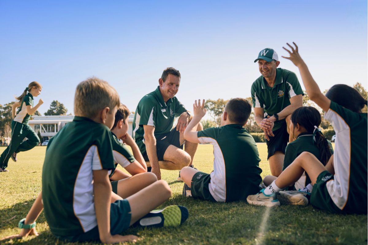 Westminster school students sat on school oval talking with their teacher.