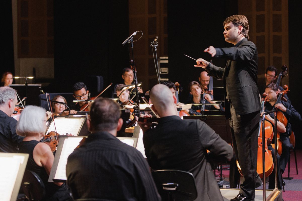 A conductor leads the Adelaide Symphony Orchestra in performance on stage