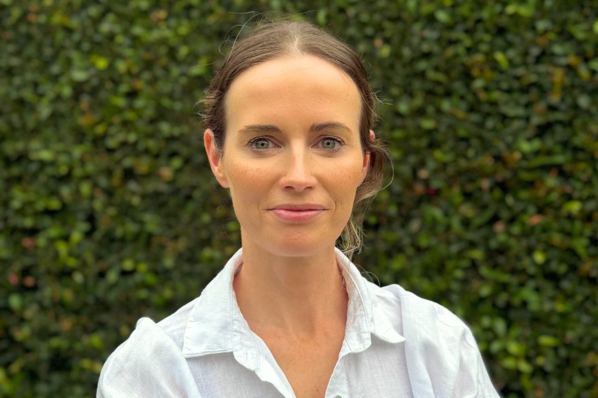 Billie Green founder Caroline Hartline pictured outdoors against a leafy green hedge backdrop.