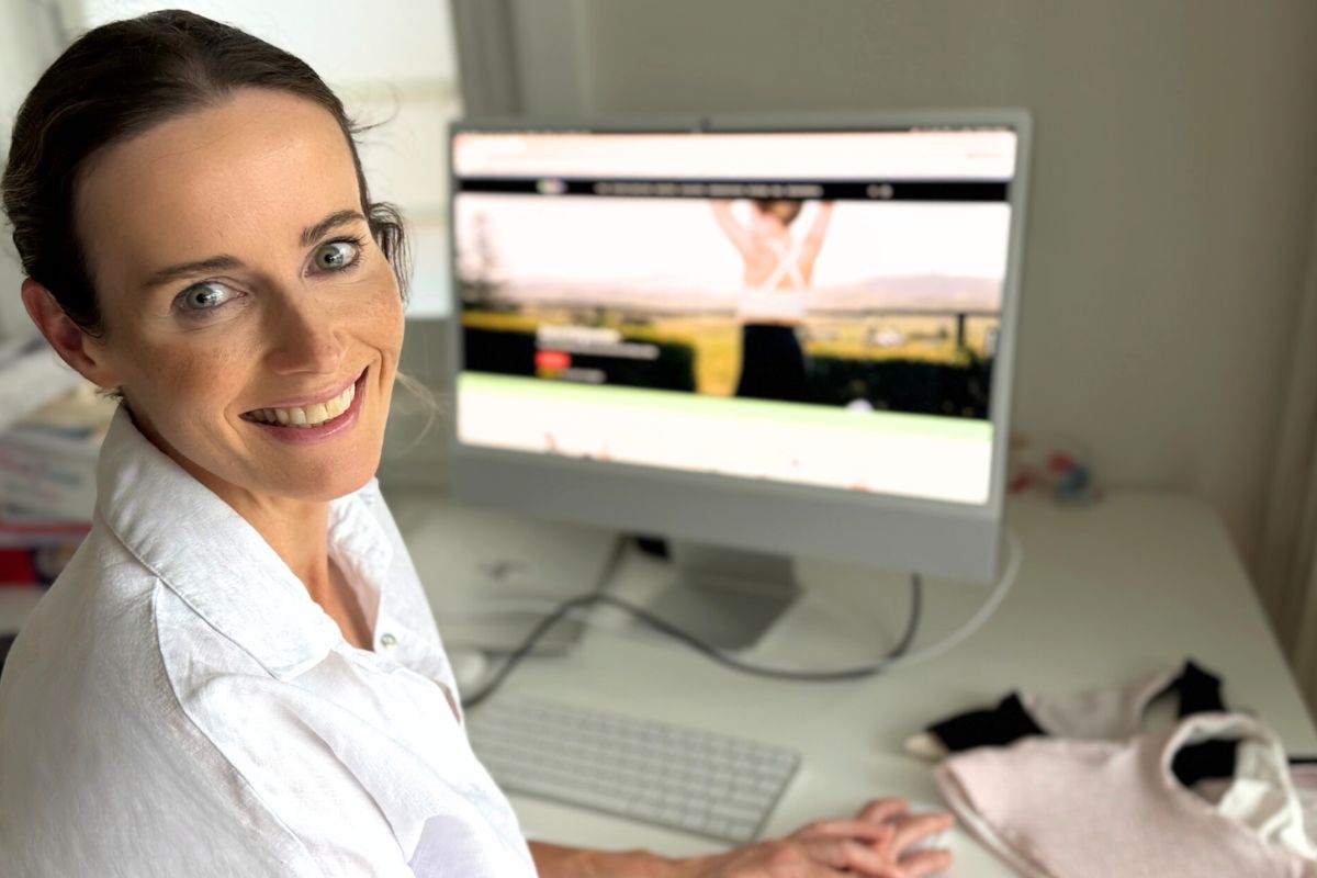 Billie Green founder Caroline Hartline smiles at her desk with the brand's website displayed on her monitor.