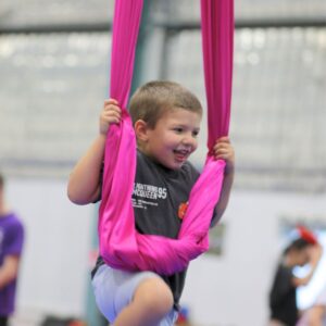 Boy laughing while swinging on aerial silks at Cirkidz, SA Circus Centre Bowden