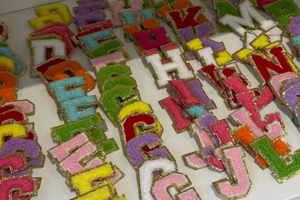 Colourful chenille letter patches in a range of colours and styles laid out on a white surface at Crafternoon Co Malvern