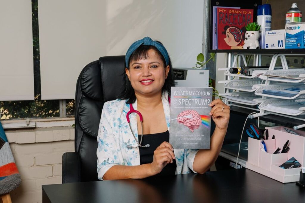 Dr Krishna Jadav Carle holding her book What’s My Colour On The Spectrum?