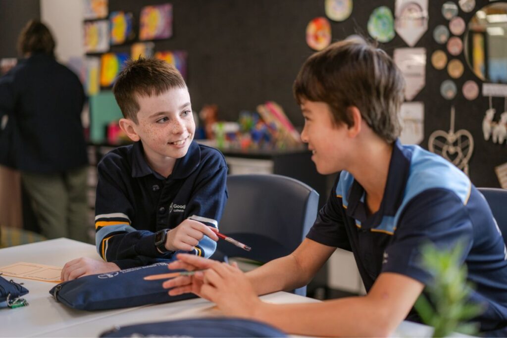 Two Good Shepherd Lutheran School primary students chatting and collaborating together at a classroom desk.