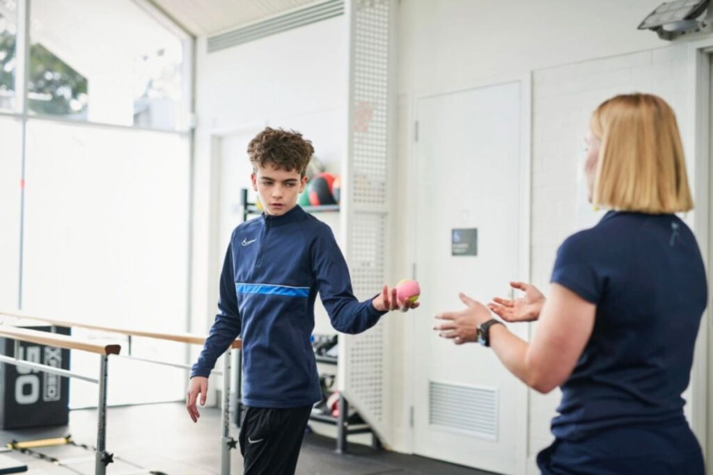 A teenage boy completing a balance and coordination exercise with a physiotherapist at NeuroPhysiotherapy Services