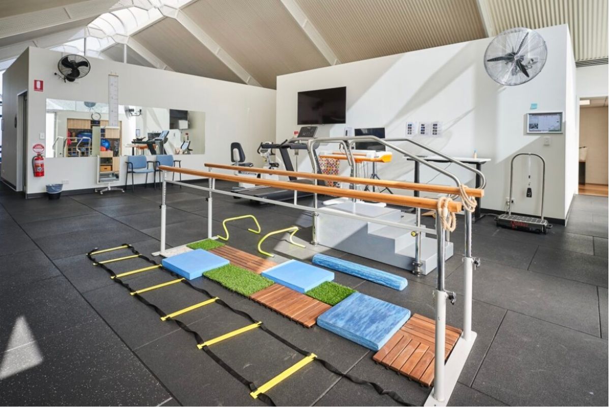 The NeuroPhysiotherapy Services studio featuring parallel bars, balance equipment and rehabilitation gym apparatus