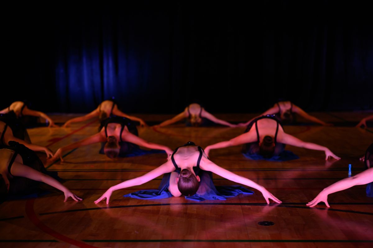 Tatachilla Lutheran College dance students performing a contemporary floor piece under dramatic stage lighting