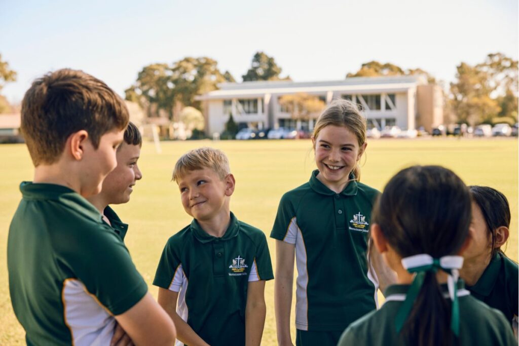 Westminster School students in green uniforms laughing and chatting together on a sunny school oval.