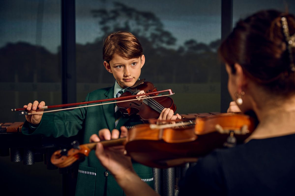 A Westminster School student plays violin during a private music lesson with a teacher.