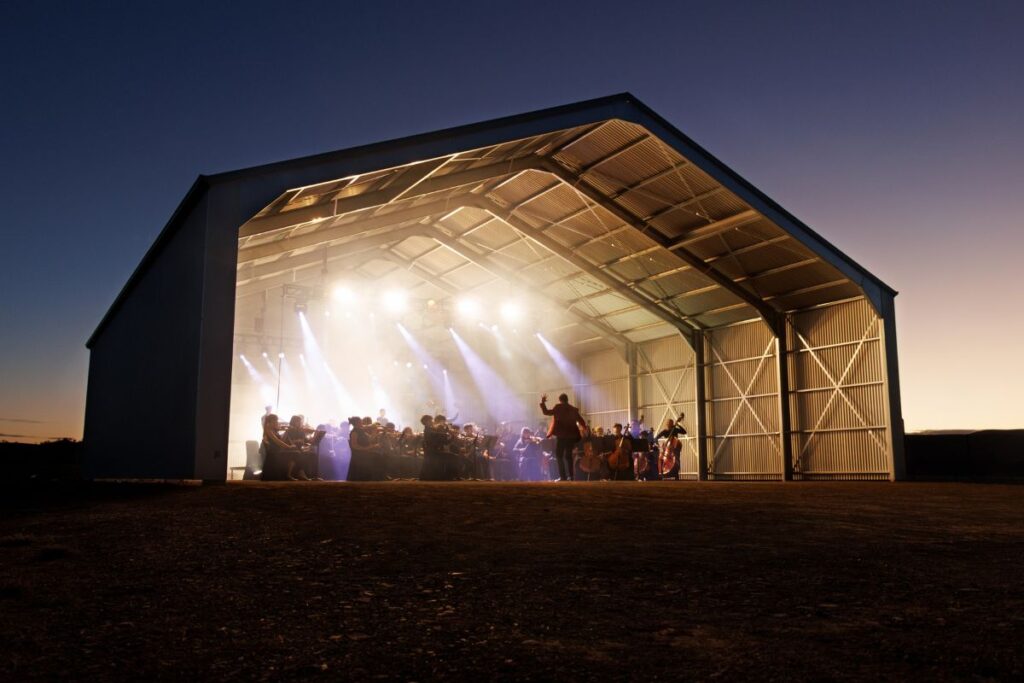 Adelaide Youth Orchestras perform at dusk inside a Stratco big shed in the Flinders Ranges